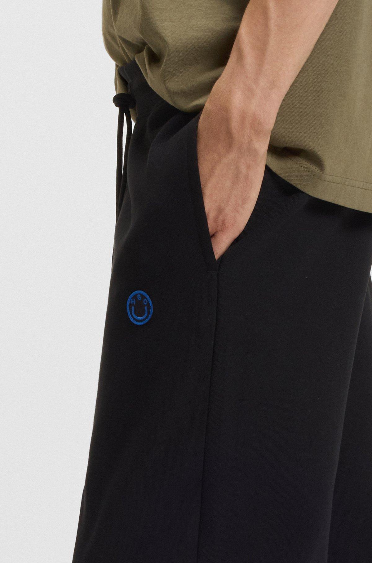 Cotton-terry tracksuit bottoms with Happy HUGO logo Product Image
