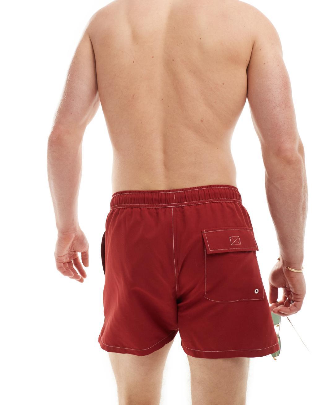 ASOS DESIGN swim shorts in short length with contrast stitch detail in burgundy Product Image