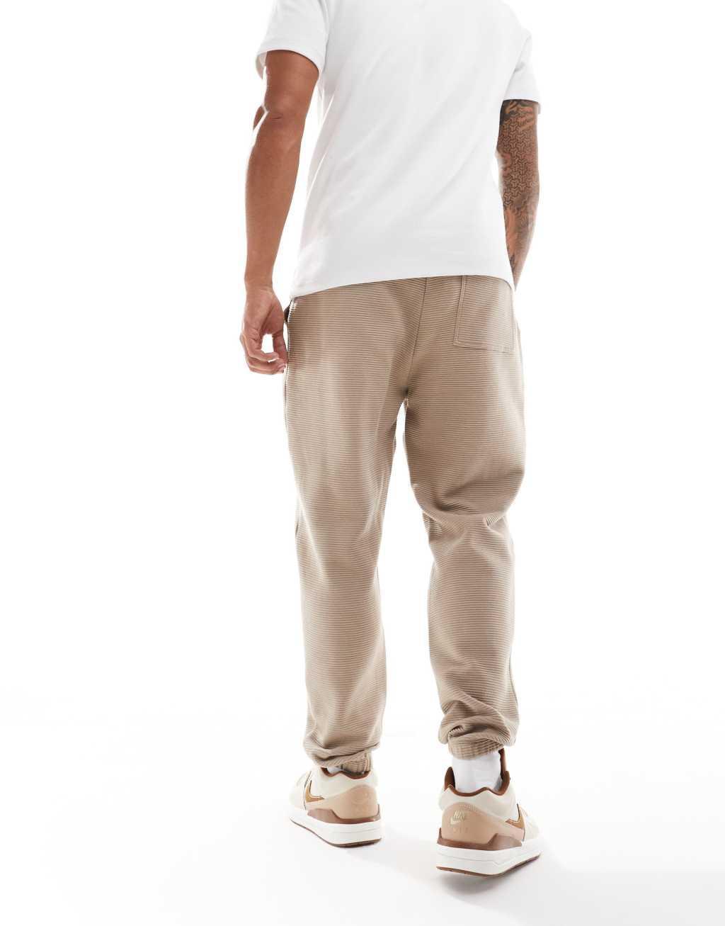 ASOS DESIGN tapered ribbed sweatpants in beige Product Image