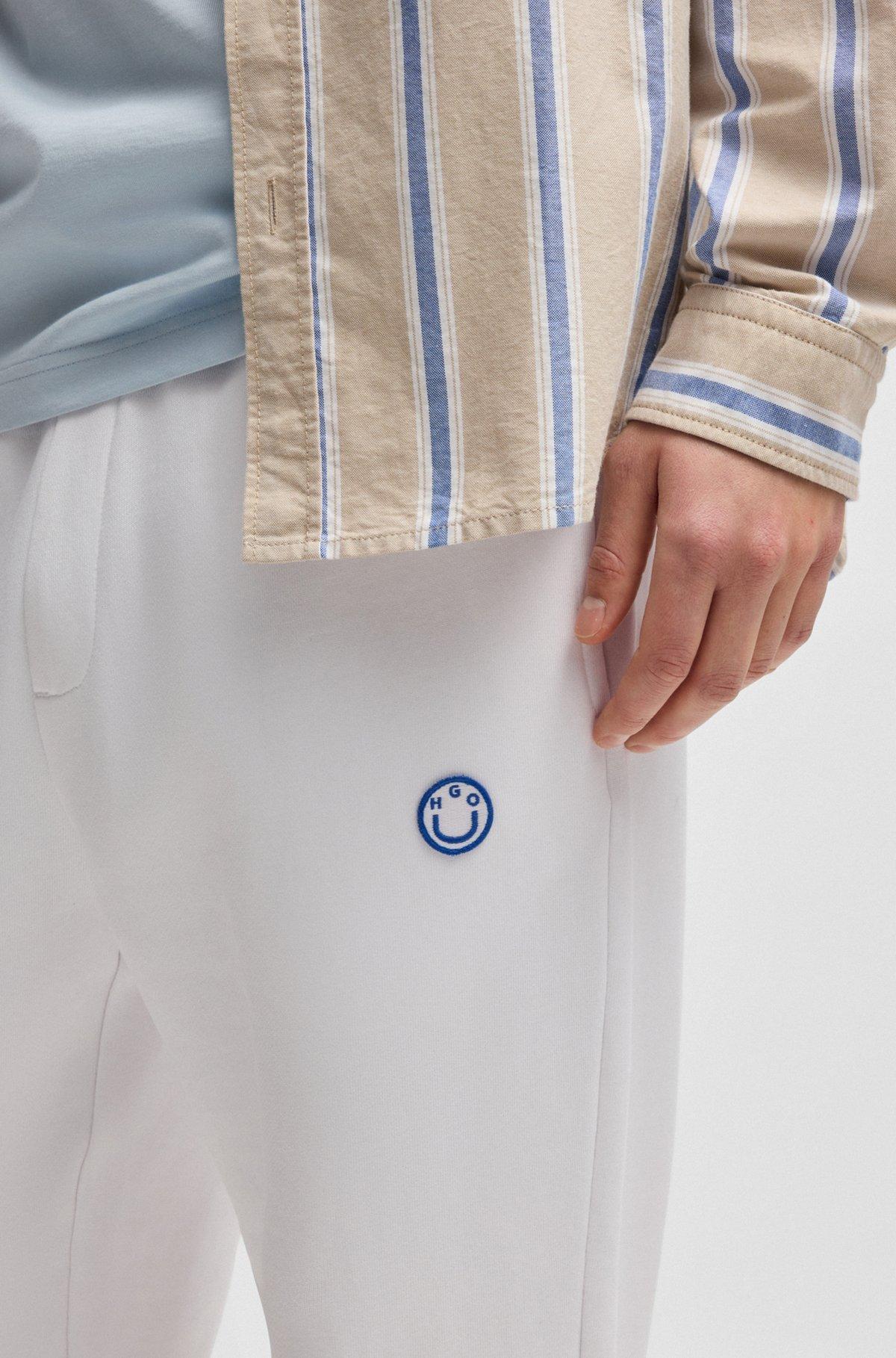 Cotton-terry tracksuit bottoms with Happy HUGO logo Product Image