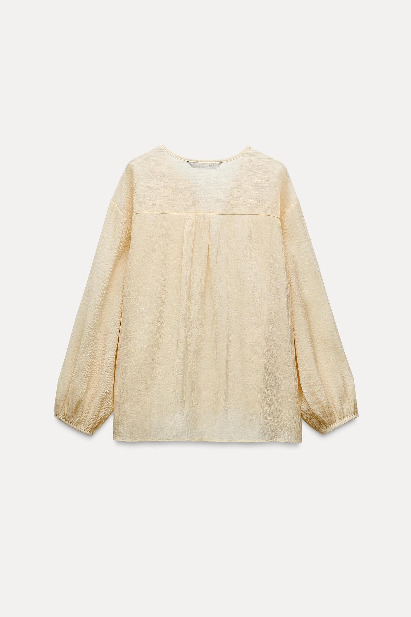 Round collar blouse with V-neck front and long balloon sleeves. Front button closure. Product Image