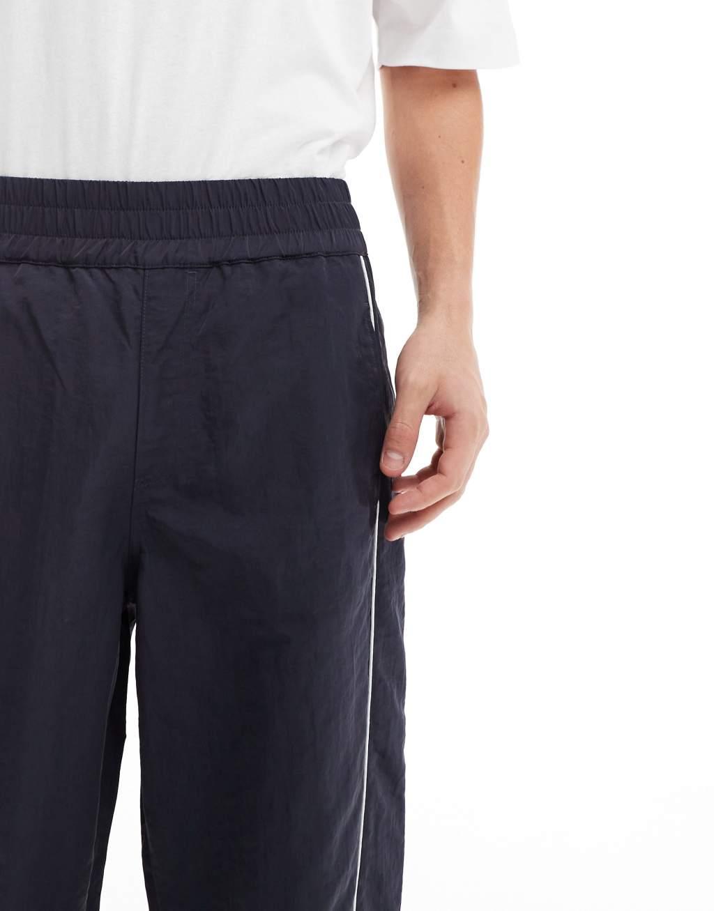 ASOS DESIGN baggy nylon track pants with white piping in navy  Product Image